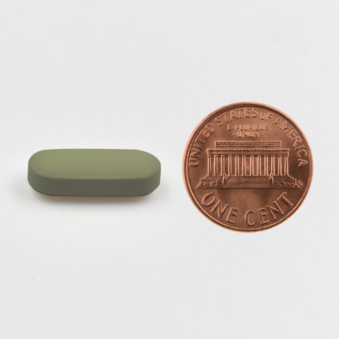 Small green rectangular object next to a U.S. penny on a white background.