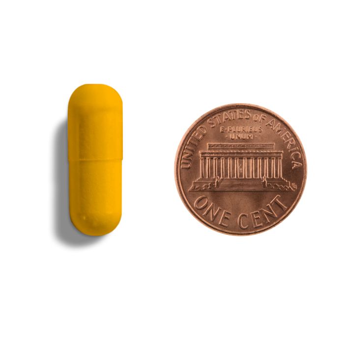 Yellow capsule and copper penny on a white background