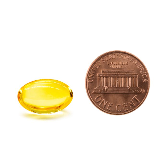 Yellow capsule and a copper penny on a white background