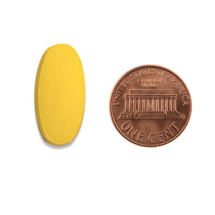 A picture of a yellow pill next to a copper penny