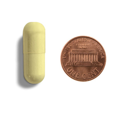 Yellow capsule next to a U.S. penny on a white background