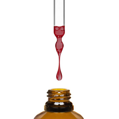 Red liquid being dripped from a dropper into an amber bottle on a white background