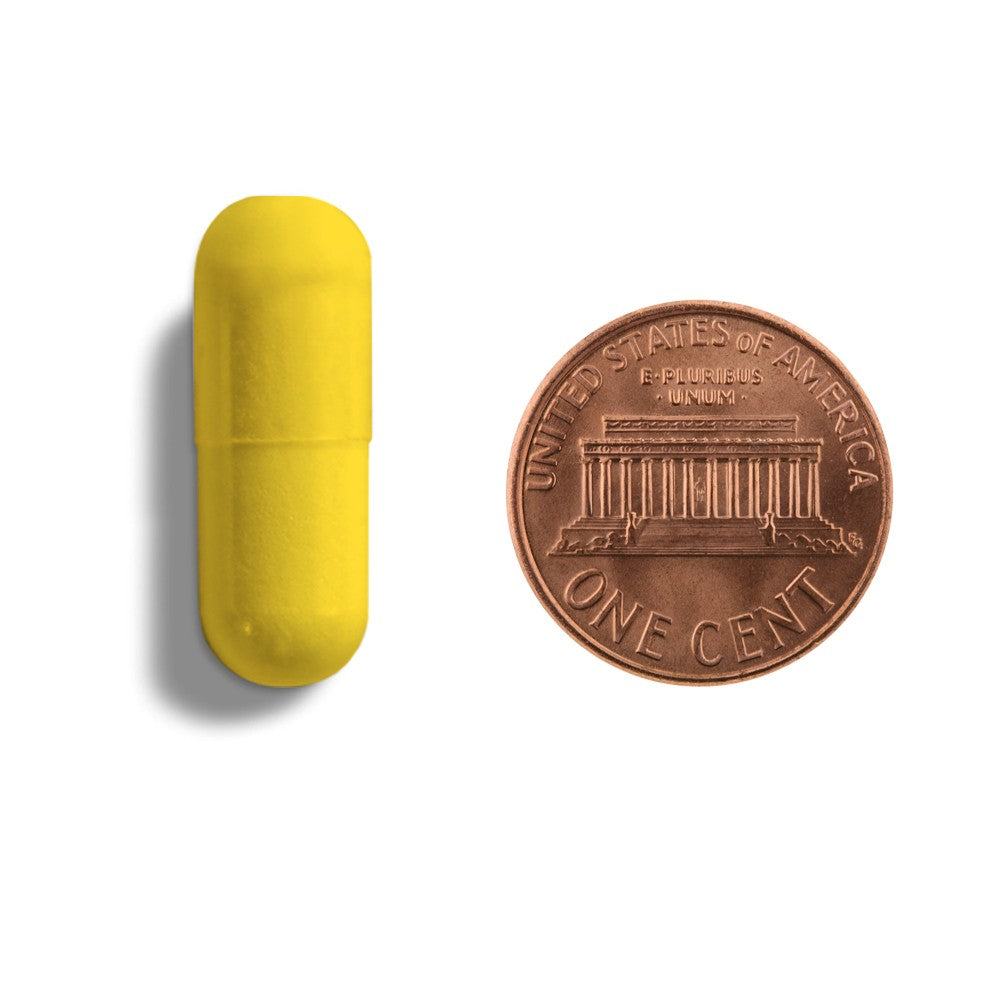 A yellow capsule next to a penny.