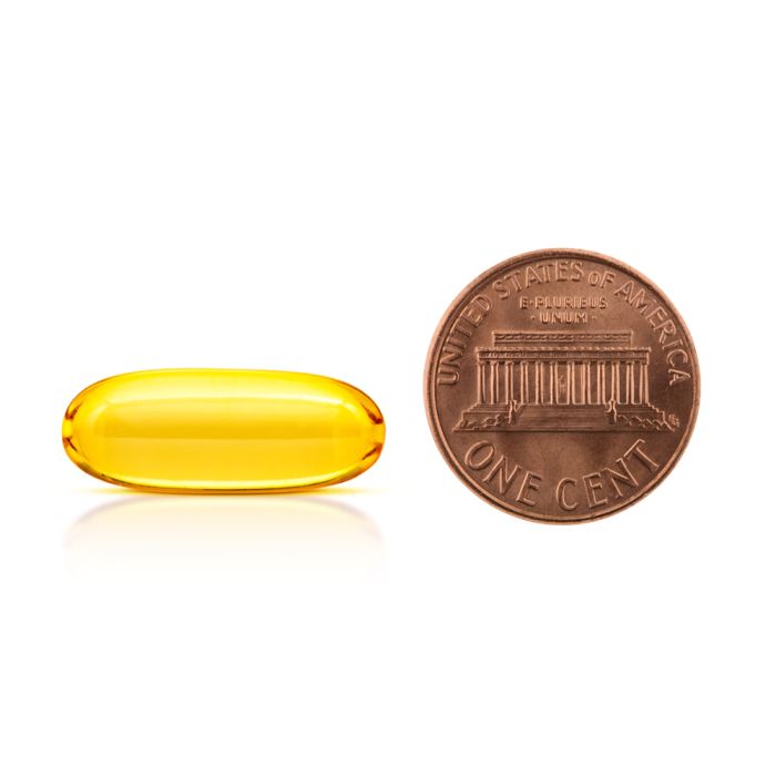 Yellow capsule next to a U.S. penny on a white background