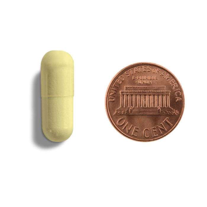 A picture of a yellow capsule next to a penny
