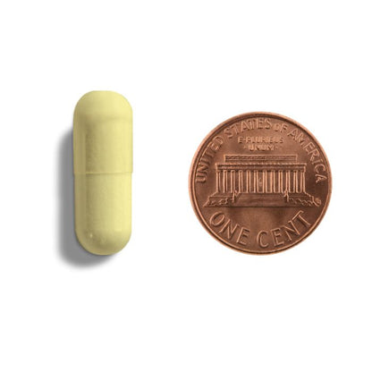 A picture of a yellow capsule next to a penny