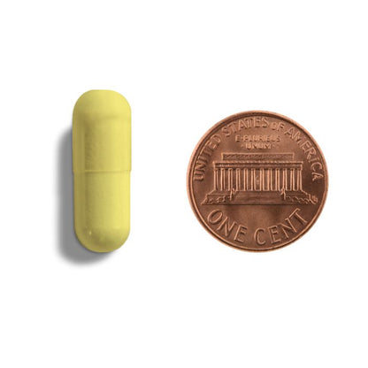 Yellow pill next to a U.S. penny on a white background