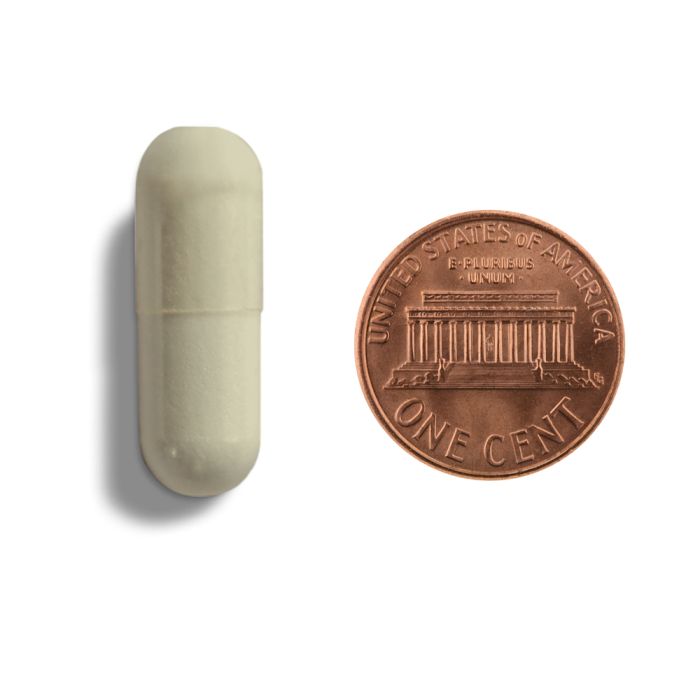 Capsule next to a penny on a white background