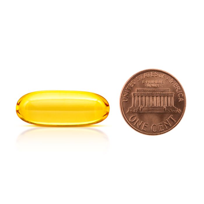Yellow capsule next to a U.S. penny on a white background