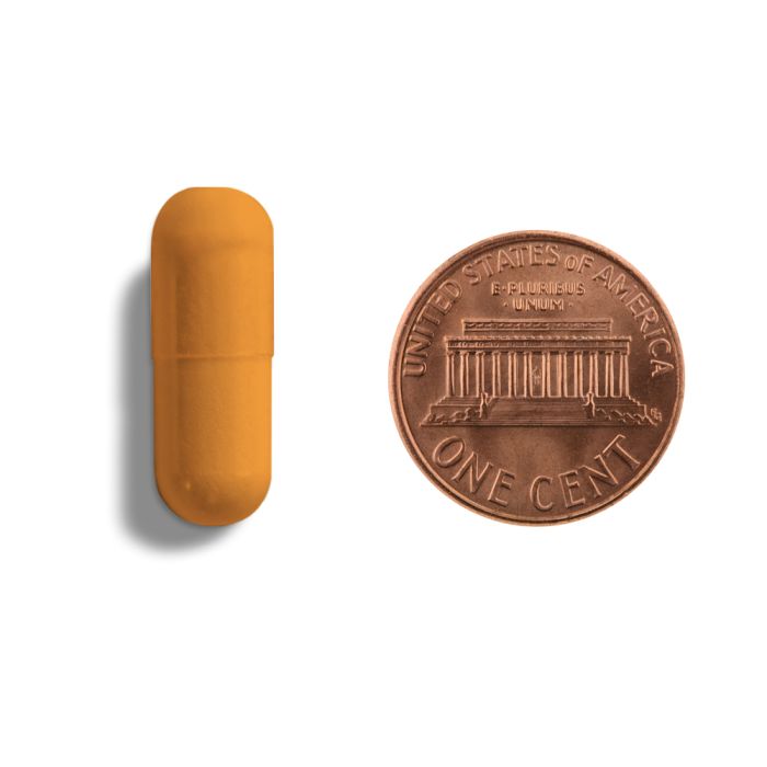 Yellow-orange pill next to a U.S. penny on a white background