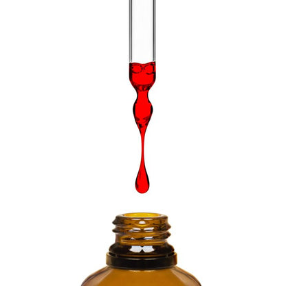 Red liquid being dripped from a dropper into an amber bottle on a white background