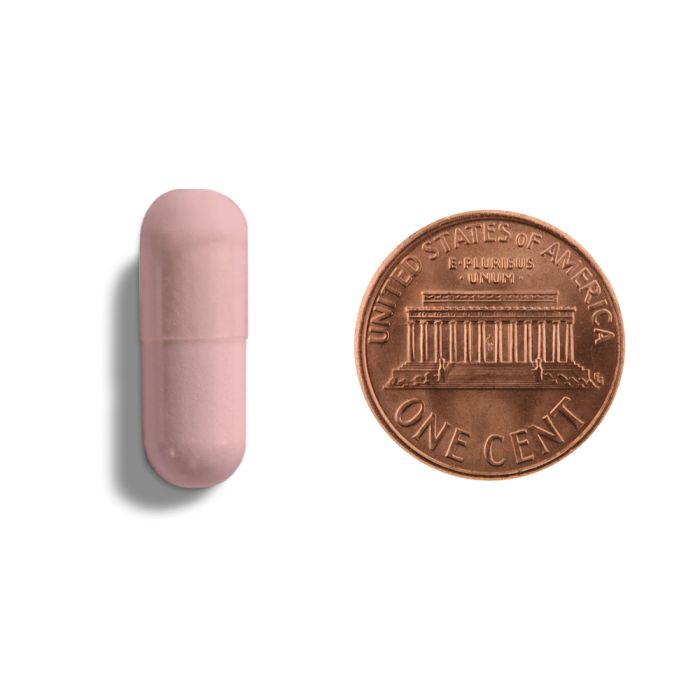 Pink cylindrical object next to a copper penny on a white background