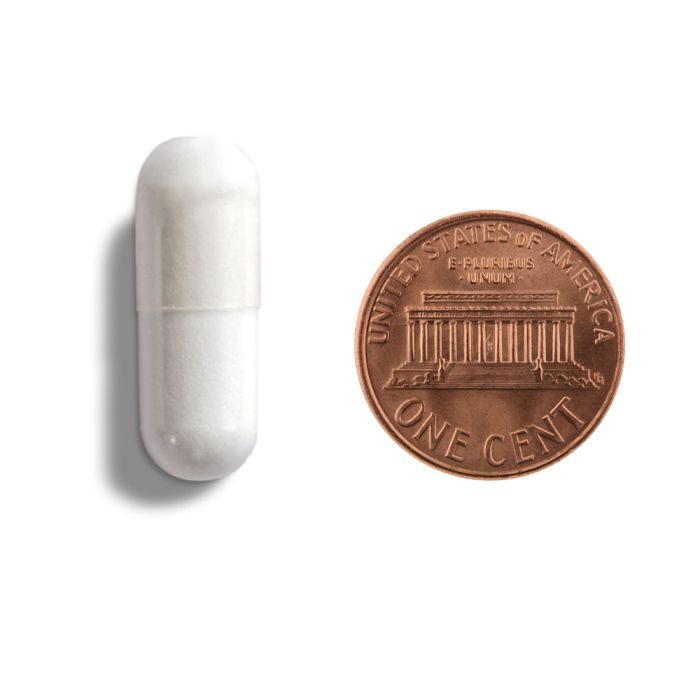 White capsule and copper penny on a white background