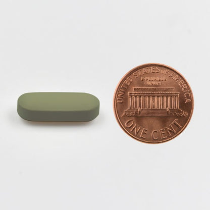 Small green rectangular object next to a U.S. penny on a white background.