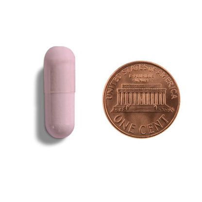 Pink capsule-shaped object next to a U.S. penny on a white background
