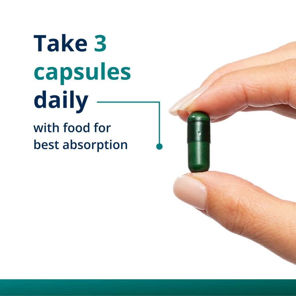Hand holding a green capsule with text about daily dosing on a white background