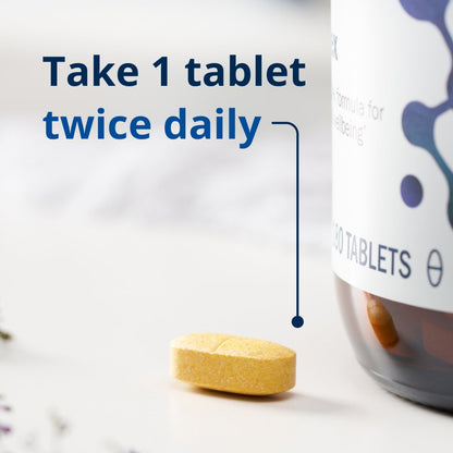 Yellow pill with text 'Take 1 tablet twice daily' and a bottle of tablets in the background.