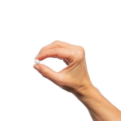 Hand holding a white pill against a white background