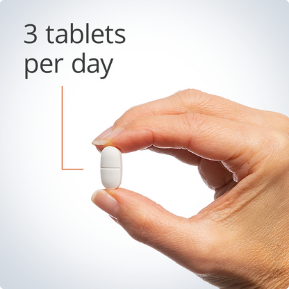 Hand holding a white pill with text '3 tablets per day' on a light gray background