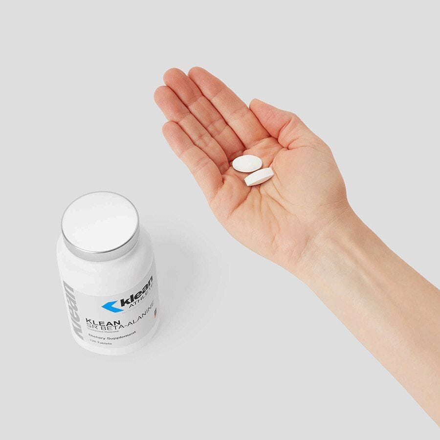 A hand holding two of the beta -alanine supplements